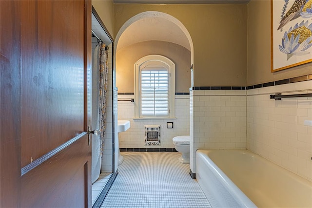 1527 NW 35th St, Oklahoma City, OK 73118 - bathroom featuring heating unit, tile walls, toilet, wainscoting, and tile patterned floors