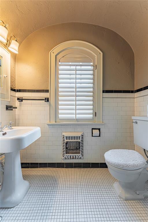 1527 NW 35th St, Oklahoma City, OK 73118 - bathroom featuring tile walls, toilet, tile patterned flooring, heating unit, and a wainscoted wall