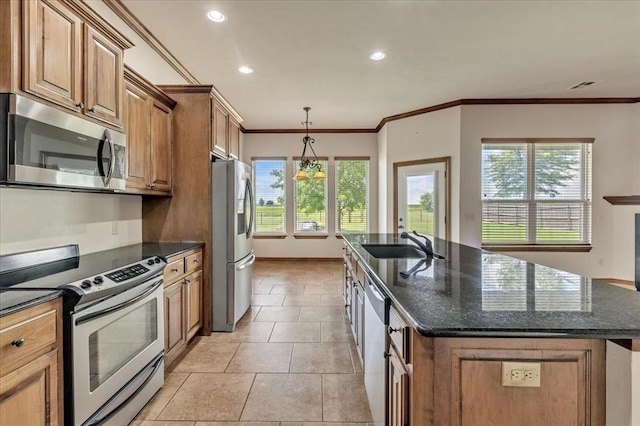 104 Southpointe Ave, Tuttle, OK 73089 - kitchen featuring appliances with stainless steel finishes, a sink, a center island with sink, brown cabinetry, and healthy amount of natural light