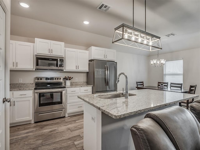 1940 Eli Ave, Tuttle, OK 73089 - kitchen featuring appliances with stainless steel finishes, a sink, white cabinets, a chandelier, and a breakfast bar area