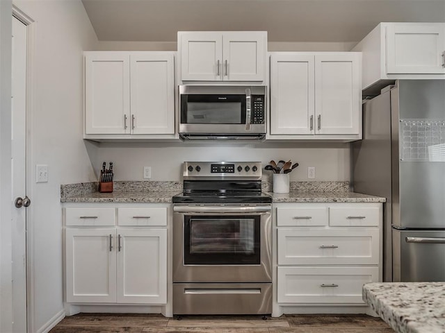 1940 Eli Ave, Tuttle, OK 73089 - kitchen featuring appliances with stainless steel finishes, white cabinetry, wood finished floors, and light stone countertops