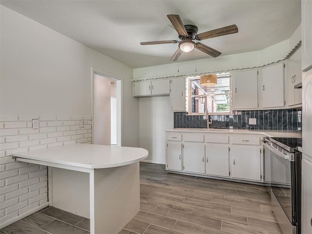 2117 SW 76th St, Oklahoma City, OK 73159 - kitchen with stainless steel electric range oven, a sink, a peninsula, a ceiling fan, and white cabinetry