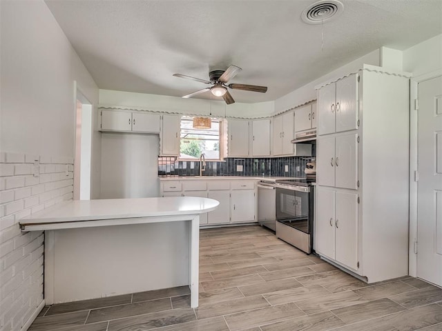 2117 SW 76th St, Oklahoma City, OK 73159 - kitchen with appliances with stainless steel finishes, a peninsula, a ceiling fan, under cabinet range hood, and white cabinets