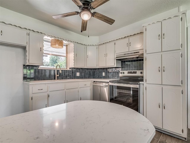 2117 SW 76th St, Oklahoma City, OK 73159 - kitchen featuring stainless steel appliances, under cabinet range hood, tasteful backsplash, a ceiling fan, and white cabinets