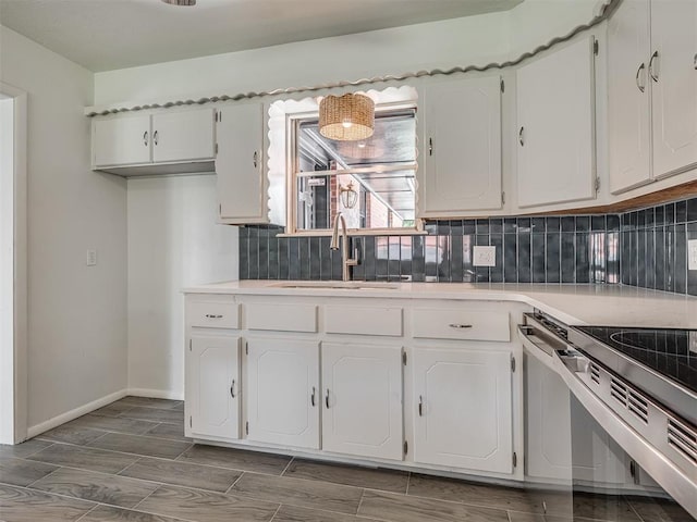 2117 SW 76th St, Oklahoma City, OK 73159 - kitchen featuring a sink, white cabinets, tasteful backsplash, and light countertops