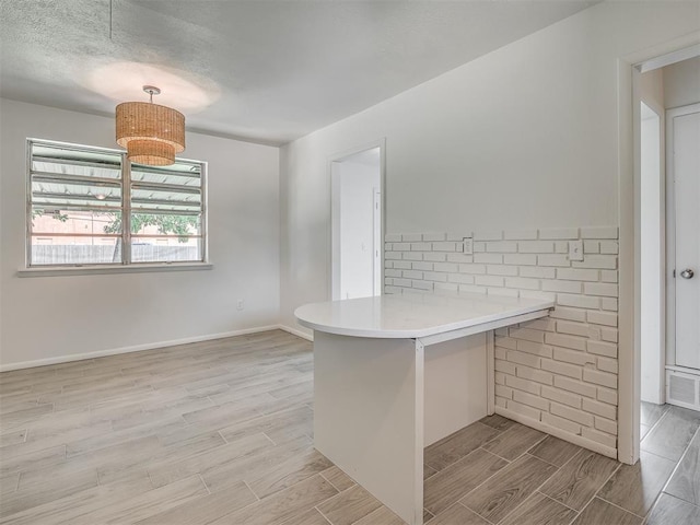 2117 SW 76th St, Oklahoma City, OK 73159 - kitchen with a peninsula, wood finish floors, light countertops, baseboards, and decorative light fixtures