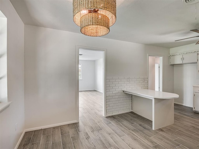 2117 SW 76th St, Oklahoma City, OK 73159 - kitchen with light wood-type flooring, a peninsula, light countertops, a chandelier, and ceiling fan