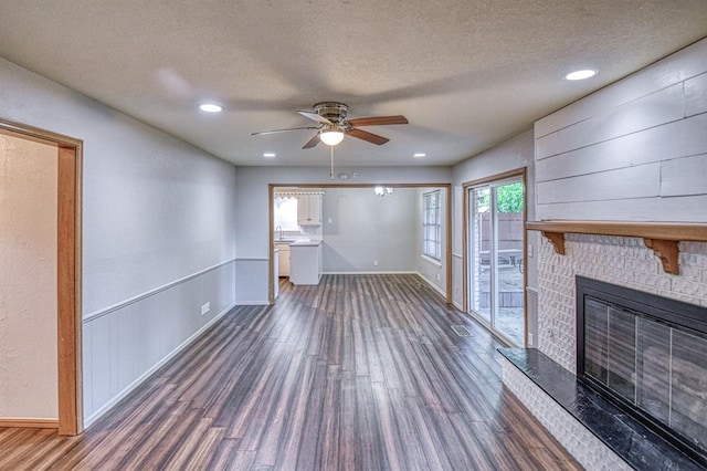 1439 Greenbriar Dr, Norman, OK 73072 - unfurnished living room featuring wood finished floors, baseboards, a fireplace, a textured ceiling, and recessed lighting