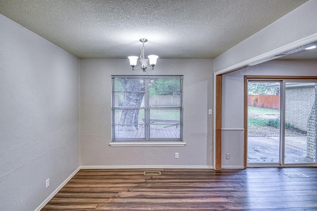 1439 Greenbriar Dr, Norman, OK 73072 - unfurnished dining area with dark wood-type flooring, a chandelier, healthy amount of natural light, and a textured ceiling