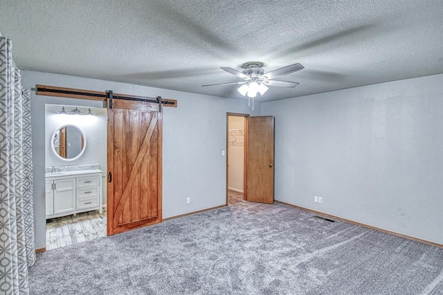 1439 Greenbriar Dr, Norman, OK 73072 - unfurnished bedroom with carpet, a spacious closet, ensuite bath, baseboards, and a textured ceiling