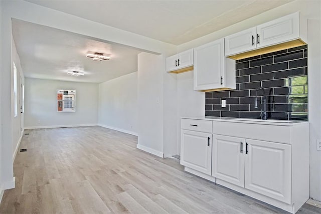 3804 NW 19th St, Oklahoma City, OK 73107 - kitchen featuring a sink, backsplash, white cabinets, light wood-type flooring, and plenty of natural light