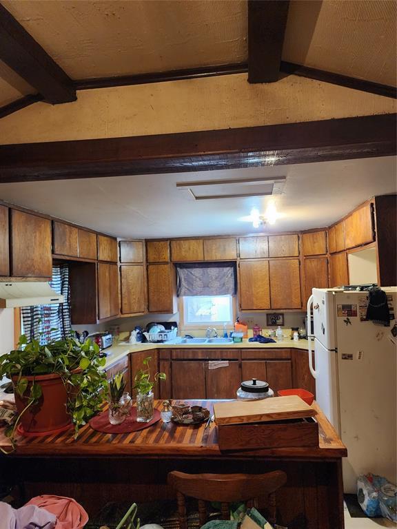 310 Mcgee St, Eufaula, OK 74432 - kitchen featuring freestanding refrigerator, brown cabinetry, under cabinet range hood, and light countertops