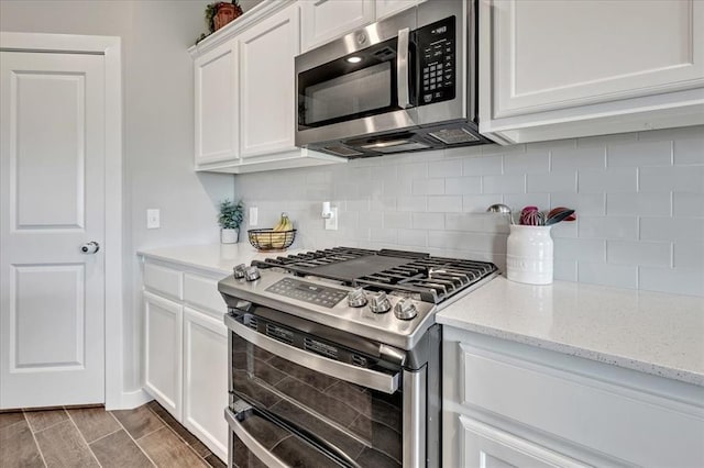 13091 Mannington Rd, Edmond, OK 73025 - kitchen with appliances with stainless steel finishes, decorative backsplash, white cabinetry, and light stone counters