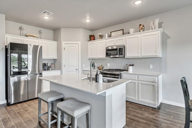 13091 Mannington Rd, Edmond, OK 73025 - kitchen with stainless steel appliances, wood tiled floors, decorative backsplash, white cabinets, and recessed lighting