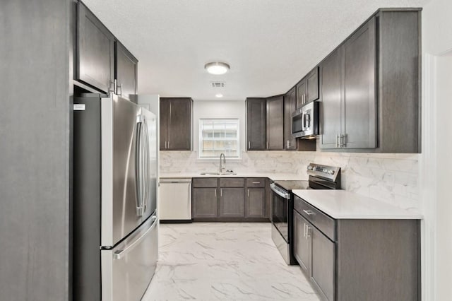 2617 SW 69th St, Oklahoma City, OK 73159 - kitchen featuring appliances with stainless steel finishes, light marble finish flooring, tasteful backsplash, light countertops, and dark brown cabinets