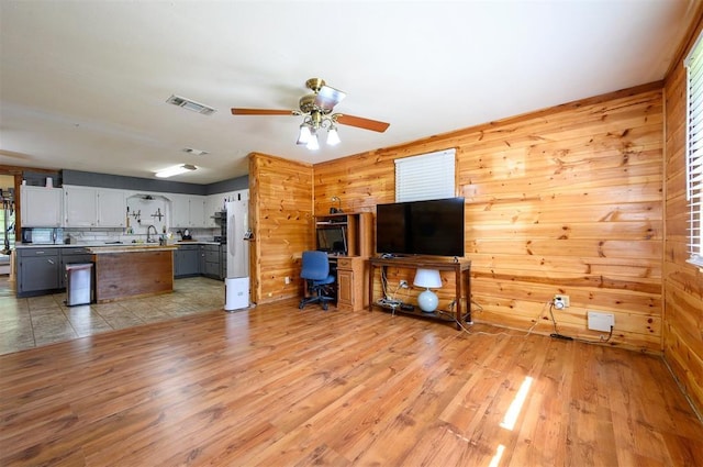 431 Canoe Rd, Broken Bow, OK 74728 - unfurnished living room featuring wooden walls, light wood-style floors, a ceiling fan, and a sink