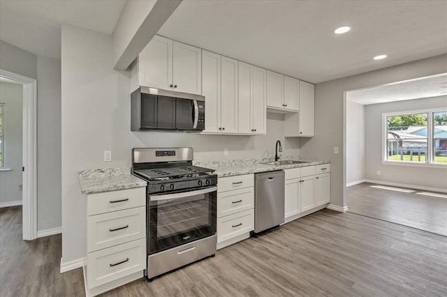 2901 Pine Ave, Oklahoma City, OK 73126 - kitchen featuring stainless steel appliances, light wood finished floors, white cabinets, recessed lighting, and light stone counters