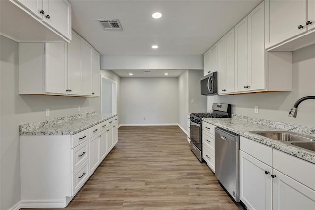 2901 Pine Ave, Oklahoma City, OK 73126 - kitchen featuring stainless steel appliances, light wood-type flooring, white cabinets, recessed lighting, and light stone counters