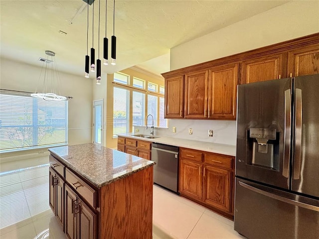 4409 Whitmere Ct, Norman, OK 73072 - kitchen featuring stainless steel appliances, light tile patterned flooring, brown cabinetry, hanging light fixtures, and a kitchen island