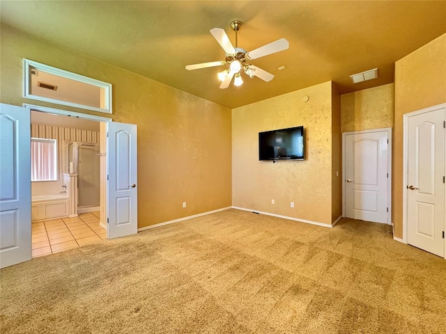 4409 Whitmere Ct, Norman, OK 73072 - unfurnished bedroom featuring carpet flooring, a textured wall, connected bathroom, tile patterned floors, and a ceiling fan