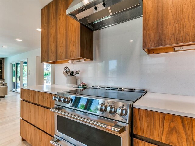 4107 Northhampton Dr, Norman, OK 73072 - kitchen featuring stainless steel electric stove, wall chimney range hood, brown cabinetry, light countertops, and modern cabinets