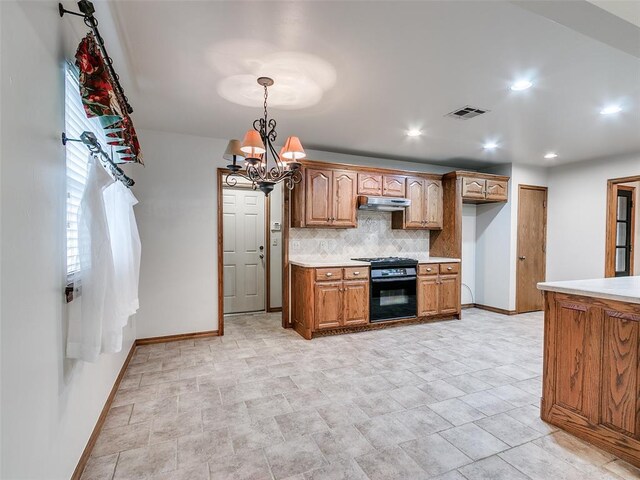 7204 Walnut Creek Dr, Oklahoma City, OK 73142 - kitchen featuring black gas stove, under cabinet range hood, tasteful backsplash, light countertops, and a chandelier