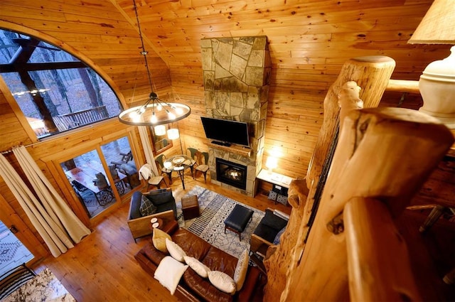 185 Marlin Dr, Broken Bow, OK 74728 - living room featuring wood finished floors, wooden walls, a stone fireplace, and a chandelier