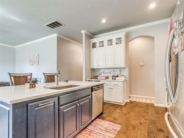 17217 Prado Dr, Oklahoma City, OK 73170 - kitchen featuring appliances with stainless steel finishes, a sink, white cabinets, crown molding, and an island with sink