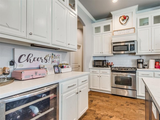 17217 Prado Dr, Oklahoma City, OK 73170 - kitchen with appliances with stainless steel finishes, wine cooler, white cabinetry, light countertops, and crown molding