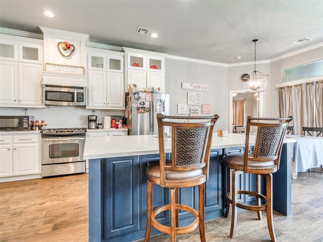 17217 Prado Dr, Oklahoma City, OK 73170 - kitchen with appliances with stainless steel finishes, white cabinets, crown molding, pendant lighting, and light wood-style flooring