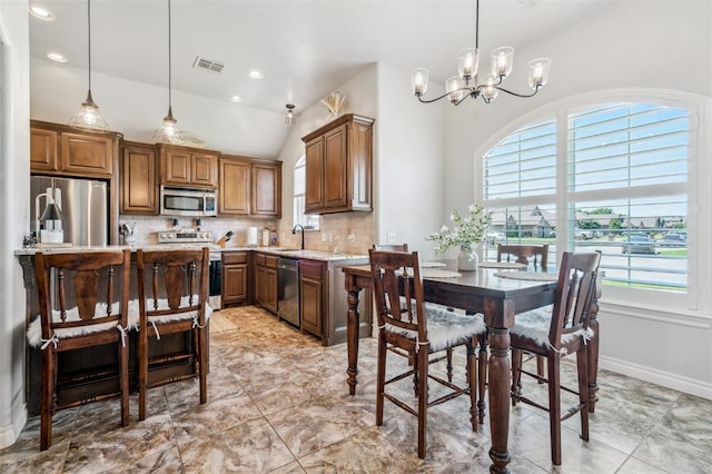908 Carol Ann Pl, Moore, OK 73160 - kitchen with appliances with stainless steel finishes, light countertops, tasteful backsplash, a chandelier, and lofted ceiling