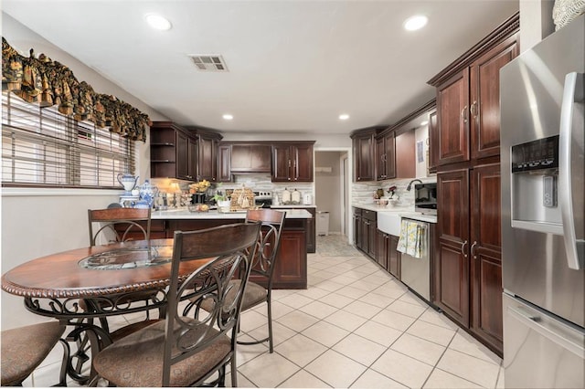 5108 NW 19th Ter, Oklahoma City, OK 73127 - kitchen with appliances with stainless steel finishes, dark brown cabinets, decorative backsplash, light countertops, and light tile patterned flooring
