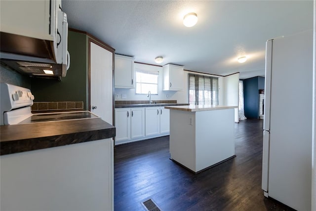 20649 E 1110th Rd, Canute, OK 73626 - kitchen with white appliances, dark countertops, dark wood-type flooring, white cabinets, and a kitchen island
