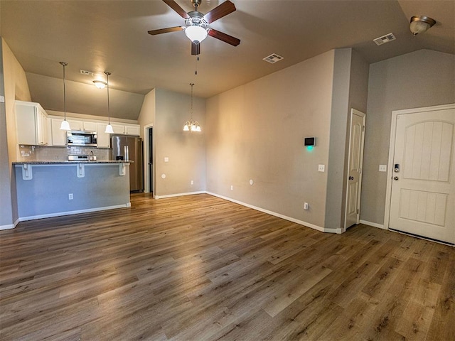 4212 Bonaparte Blvd, Midwest City, OK 73110 - unfurnished living room with lofted ceiling, ceiling fan, baseboards, dark wood-type flooring, and a chandelier
