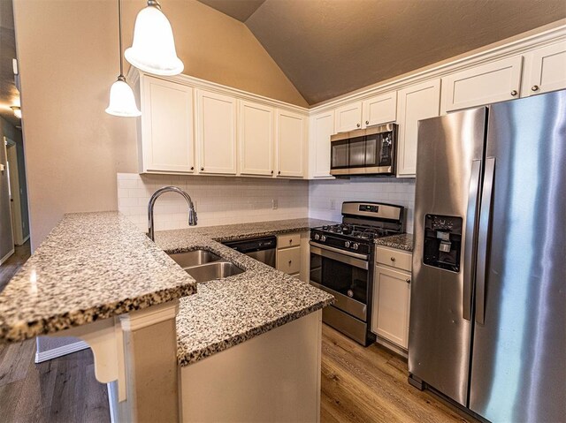 4212 Bonaparte Blvd, Midwest City, OK 73110 - kitchen with appliances with stainless steel finishes, a peninsula, a sink, vaulted ceiling, and wood finished floors