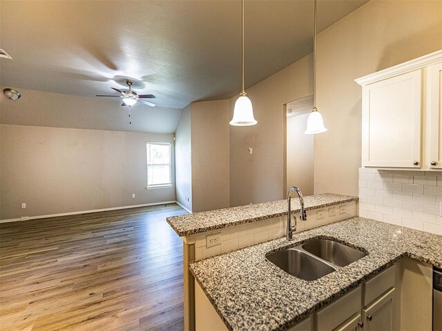 4212 Bonaparte Blvd, Midwest City, OK 73110 - kitchen featuring a sink, wood finished floors, tasteful backsplash, a peninsula, and light stone counters
