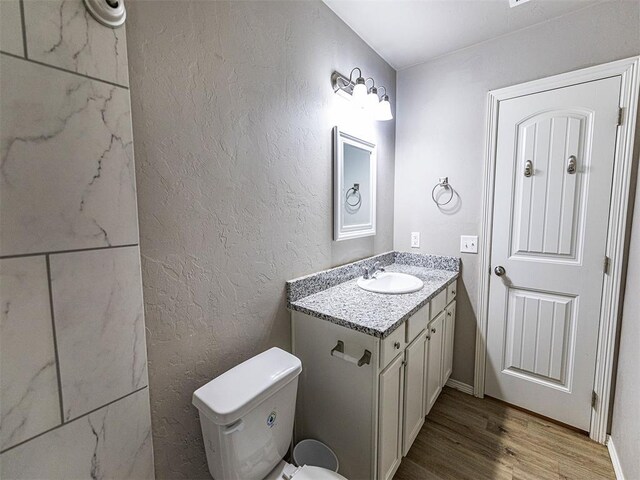 4212 Bonaparte Blvd, Midwest City, OK 73110 - half bathroom featuring wood finished floors, vanity, toilet, a textured wall, and baseboards