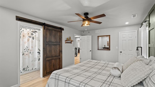 10506 W Smith Rd, El Reno, OK 73036 - bedroom featuring a barn door, light wood-type flooring, ceiling fan, and recessed lighting
