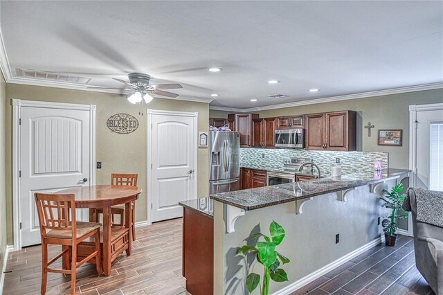 13086 240th, Blanchard, OK 73010 - kitchen featuring stainless steel appliances, a breakfast bar area, a peninsula, wood tiled floors, and dark stone countertops