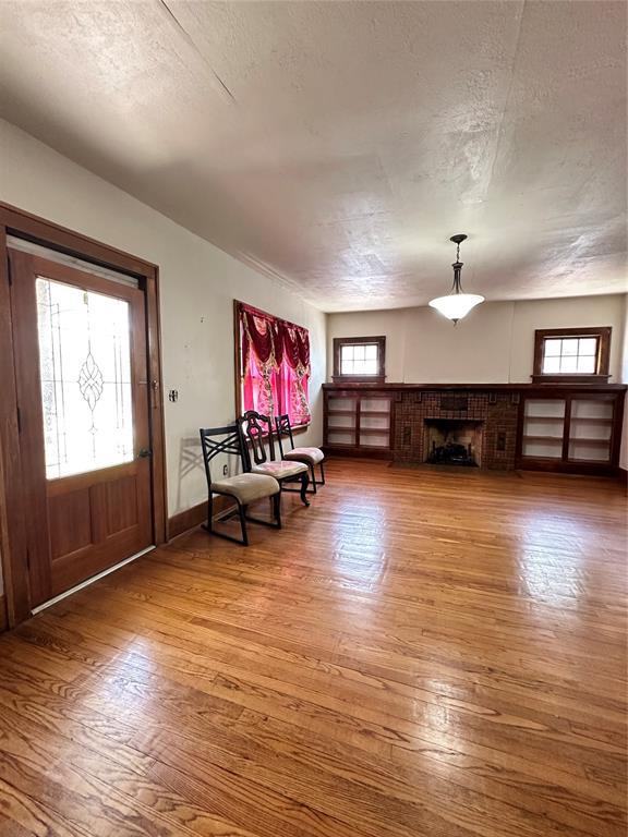 2001 NW 18th St, Oklahoma City, OK 73106 - entrance foyer featuring wood finished floors, a textured ceiling, and a brick fireplace