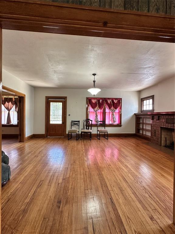 2001 NW 18th St, Oklahoma City, OK 73106 - unfurnished living room featuring wood finished floors and a fireplace