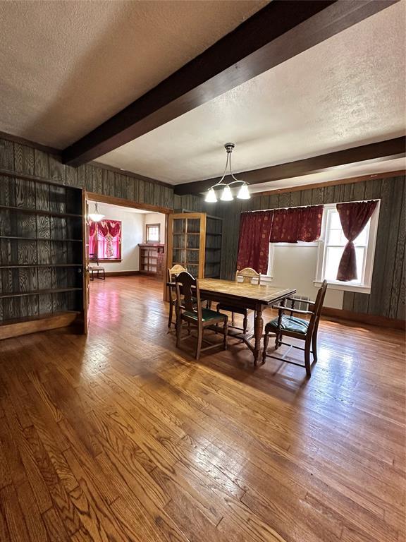 2001 NW 18th St, Oklahoma City, OK 73106 - dining room with a textured ceiling, wood finished floors, wood walls, beam ceiling, and a chandelier