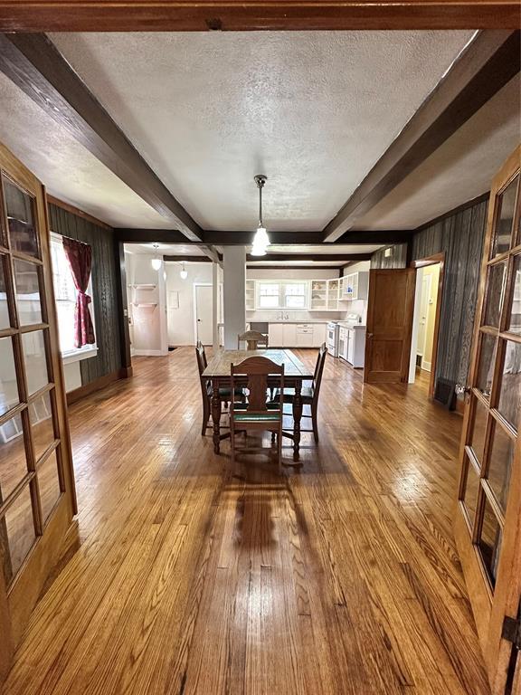 2001 NW 18th St, Oklahoma City, OK 73106 - dining room with beamed ceiling, wood finished floors, a textured ceiling, and wooden walls