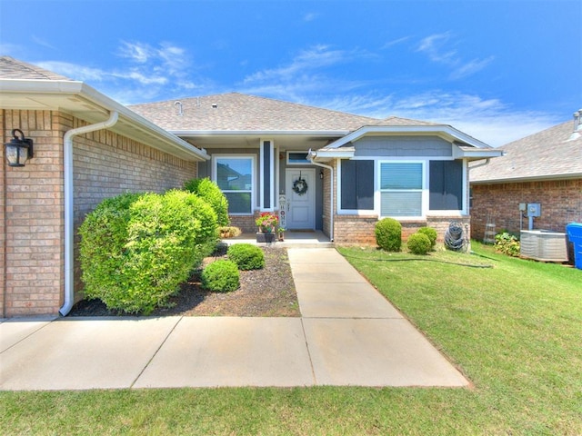 3911 Wiltshire Dr, Norman, OK 73026 - view of front facade with brick siding, central AC unit, a front lawn, and roof with shingles