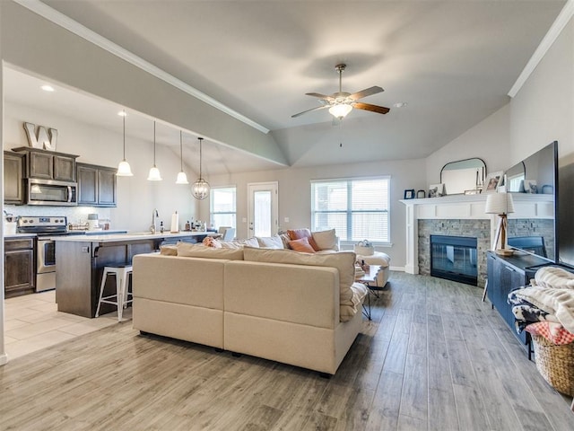 3911 Wiltshire Dr, Norman, OK 73026 - living area with vaulted ceiling, light wood finished floors, a fireplace, a ceiling fan, and crown molding