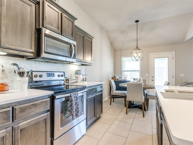 3911 Wiltshire Dr, Norman, OK 73026 - kitchen featuring stainless steel appliances, light countertops, dark brown cabinets, backsplash, and vaulted ceiling