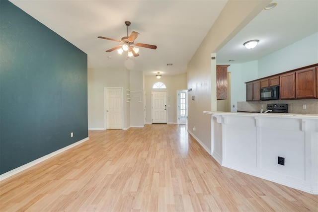 5600 Darla Dr, Oklahoma City, OK 73135 - kitchen with black microwave, electric stove, a ceiling fan, light wood finished floors, and backsplash