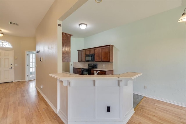 5600 Darla Dr, Oklahoma City, OK 73135 - kitchen with black appliances, light wood-style floors, and a breakfast bar area