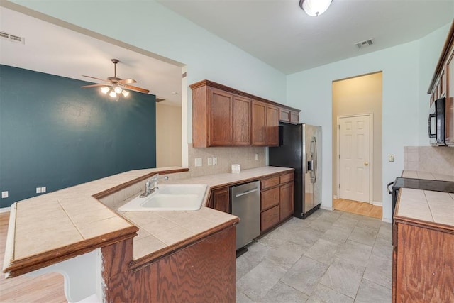 5600 Darla Dr, Oklahoma City, OK 73135 - kitchen with stainless steel appliances, a peninsula, tile countertops, a ceiling fan, and tasteful backsplash