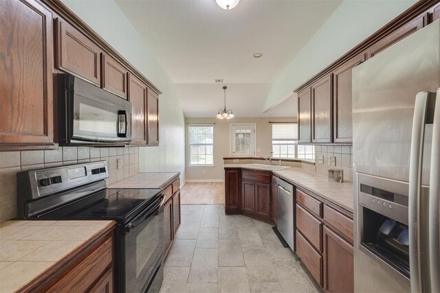 5600 Darla Dr, Oklahoma City, OK 73135 - kitchen with stainless steel appliances, tile countertops, a chandelier, tasteful backsplash, and a peninsula